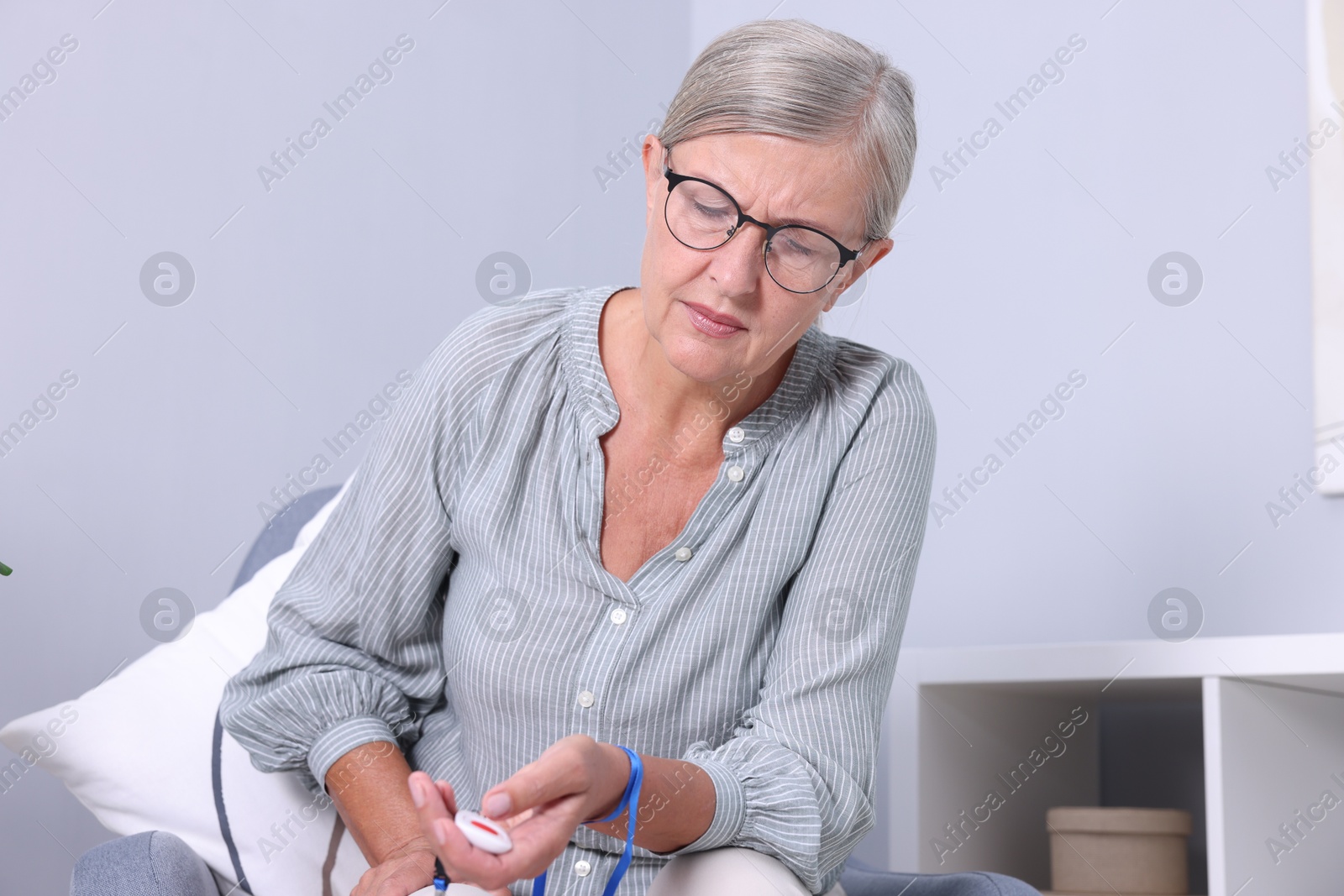 Photo of Senior woman pressing emergency call button at home