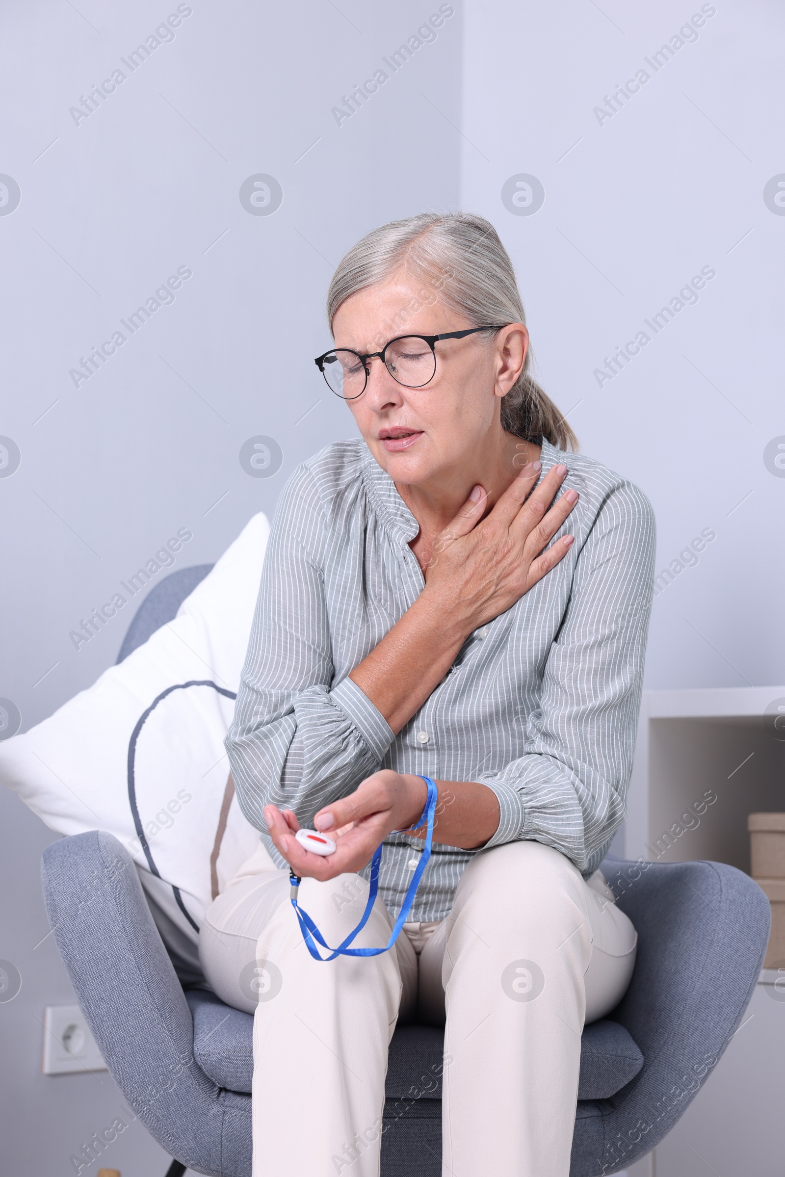 Photo of Senior woman with emergency call button suffering from neck pain at home