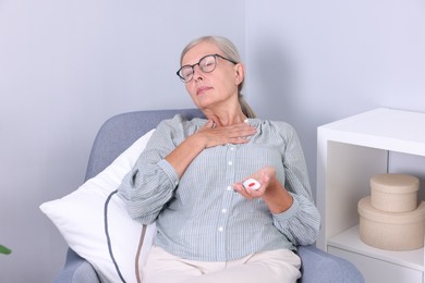Photo of Senior woman suffering from neck pain holding emergency call button at home