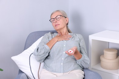 Senior woman suffering from neck pain holding emergency call button at home