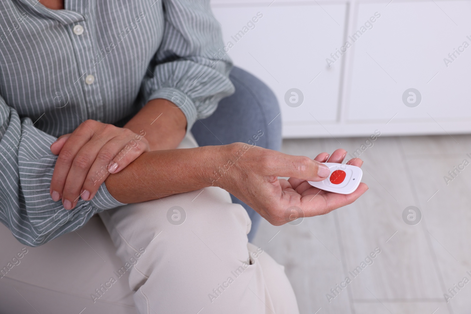 Photo of Senior woman pressing emergency call button at home, closeup