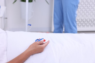 Photo of Senior woman with emergency call button and nurse setting IV drip in hospital, closeup