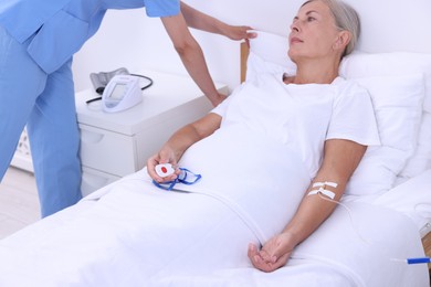 Senior woman with emergency call button and nurse in hospital