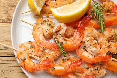 Photo of Skewers with delicious grilled shrimps served on wooden table, top view