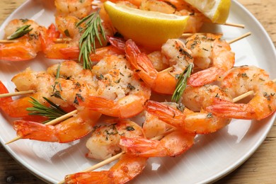 Photo of Skewers with delicious grilled shrimps served on wooden table, closeup