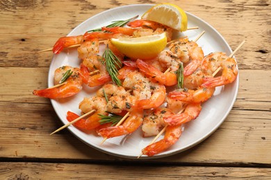 Photo of Skewers with delicious grilled shrimps served on wooden table