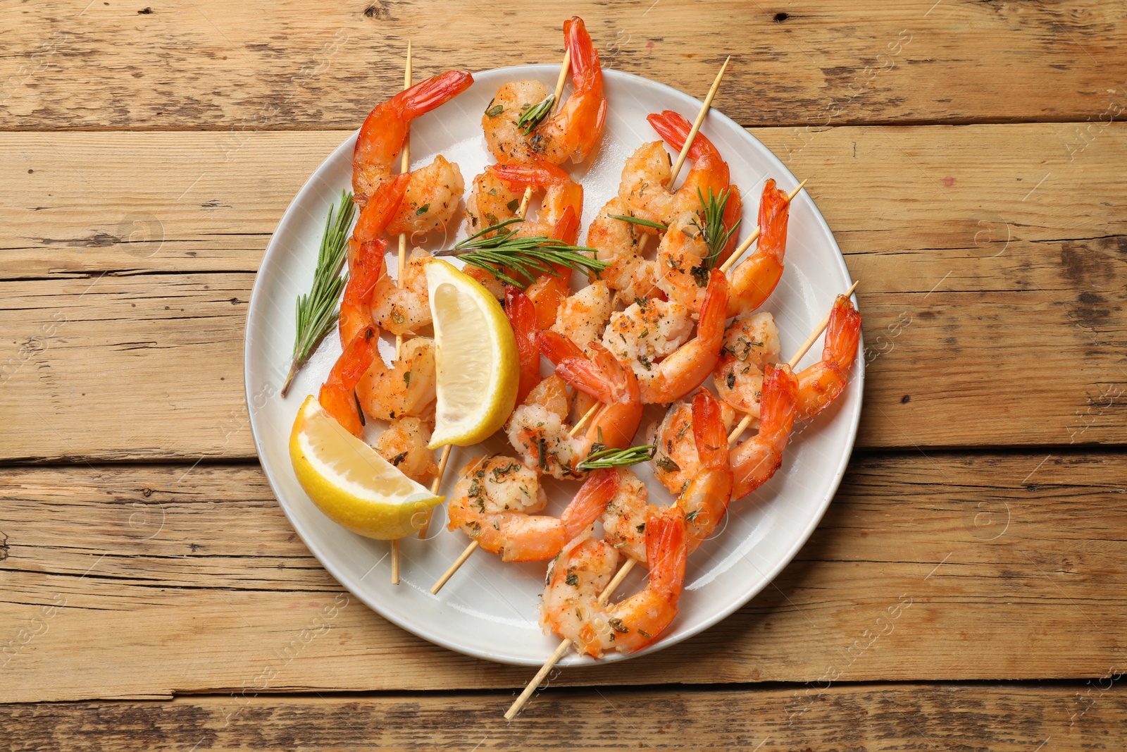 Photo of Skewers with delicious grilled shrimps served on wooden table, top view