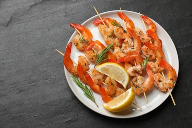 Photo of Skewers with delicious grilled shrimps served on black table, top view. Space for text