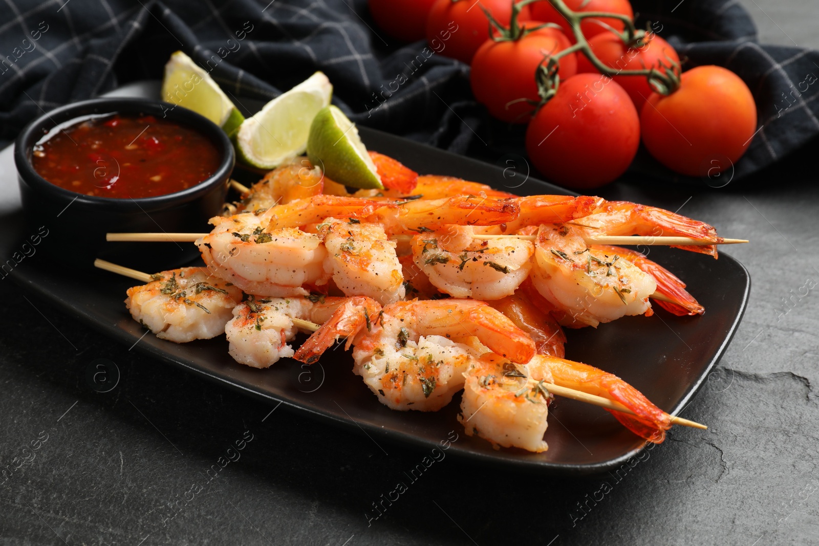 Photo of Skewers with delicious grilled shrimps served on black table