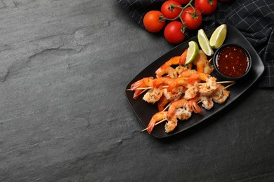 Photo of Skewers with delicious grilled shrimps served on black table, flat lay. Space for text