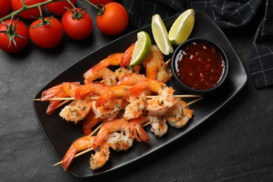 Photo of Skewers with delicious grilled shrimps served on black table, flat lay