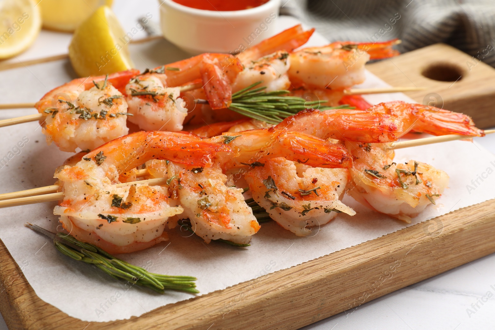 Photo of Skewers with delicious grilled shrimps on white table, closeup