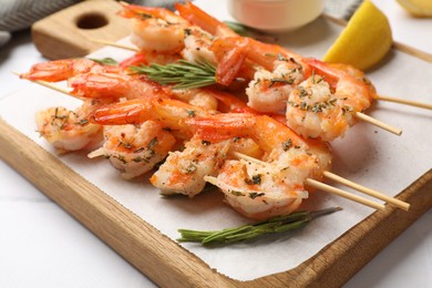 Photo of Skewers with delicious grilled shrimps on white table, closeup