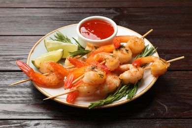 Photo of Delicious grilled shrimp skewers served with sauce and lime on wooden table