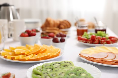 Different meals served on white table indoors, closeup. Buffet menu