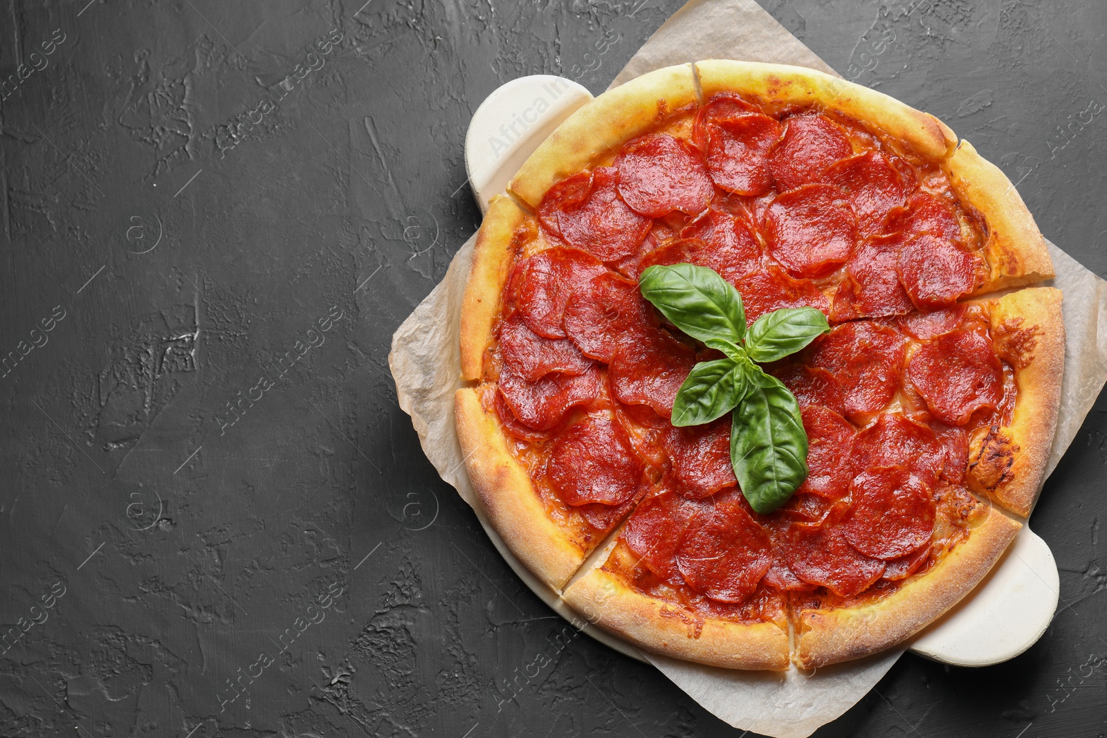 Photo of Tasty pepperoni pizza on black textured table, top view. Space for text