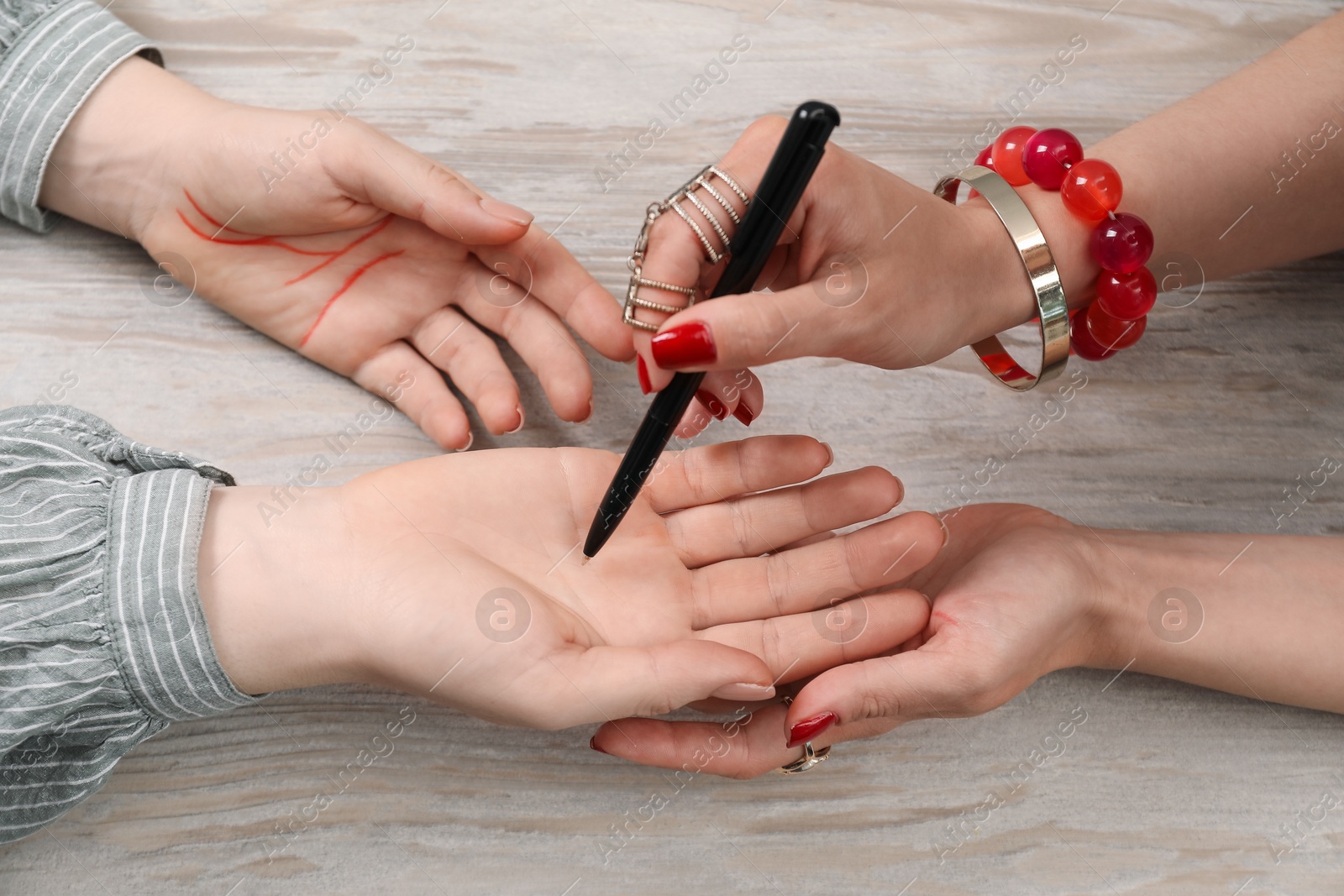 Photo of Fortune teller reading lines on woman's palm at wooden table, closeup. Chiromancy