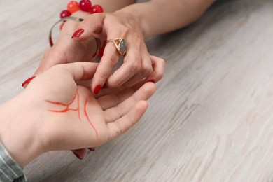 Photo of Fortune teller reading lines on woman's palm at wooden table, closeup. Chiromancy