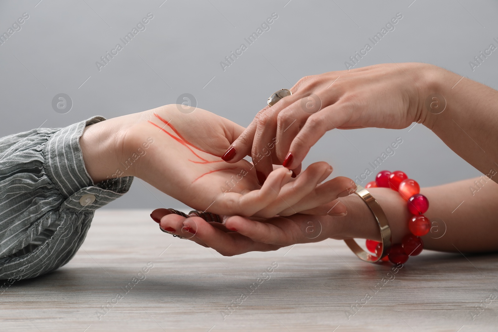 Photo of Fortune teller reading lines on woman's palm at wooden table, closeup. Chiromancy