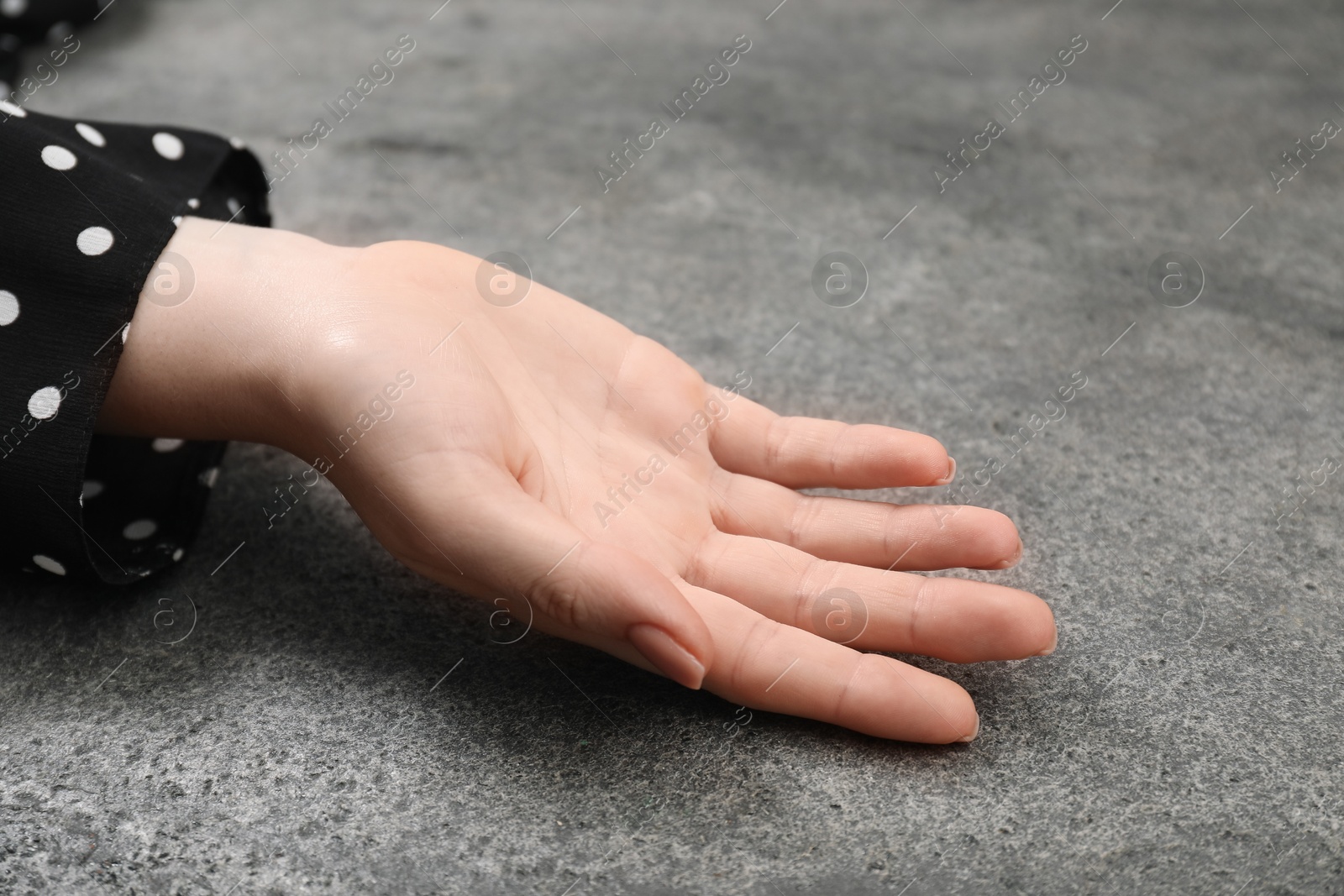 Photo of Woman showing palm at grey table, closeup. Chiromancy and foretelling