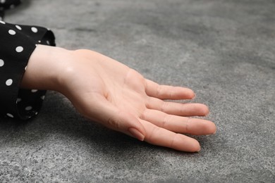 Woman showing palm at grey table, closeup. Chiromancy and foretelling