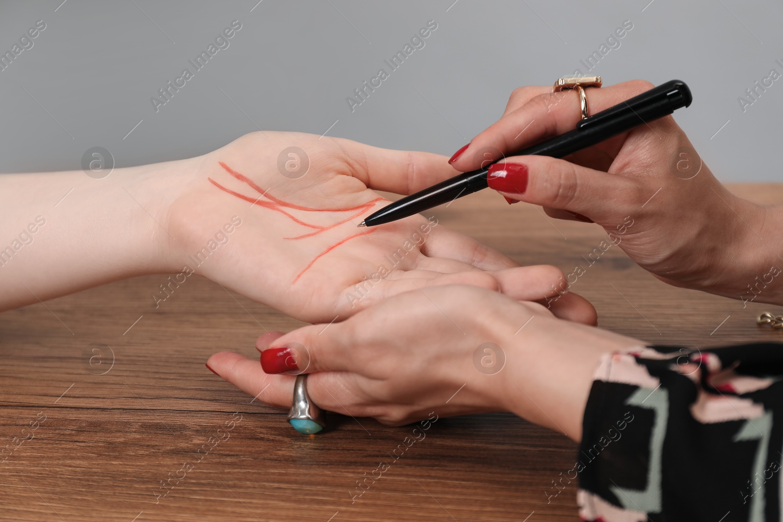 Photo of Fortune teller reading lines on woman's palm at wooden table, closeup. Chiromancy