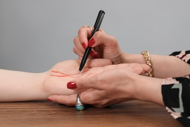 Photo of Fortune teller reading lines on woman's palm at wooden table, closeup. Chiromancy