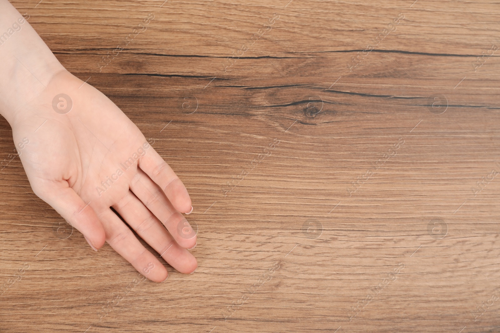 Photo of Woman showing palm at wooden table, top view with space for text. Chiromancy and foretelling