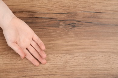 Photo of Woman showing palm at wooden table, top view with space for text. Chiromancy and foretelling