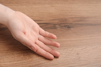 Chiromancy and foretelling. Woman showing palm at wooden table, closeup. Space for text