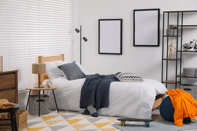 Photo of Teen's room interior with modern furniture and empty frames on wall