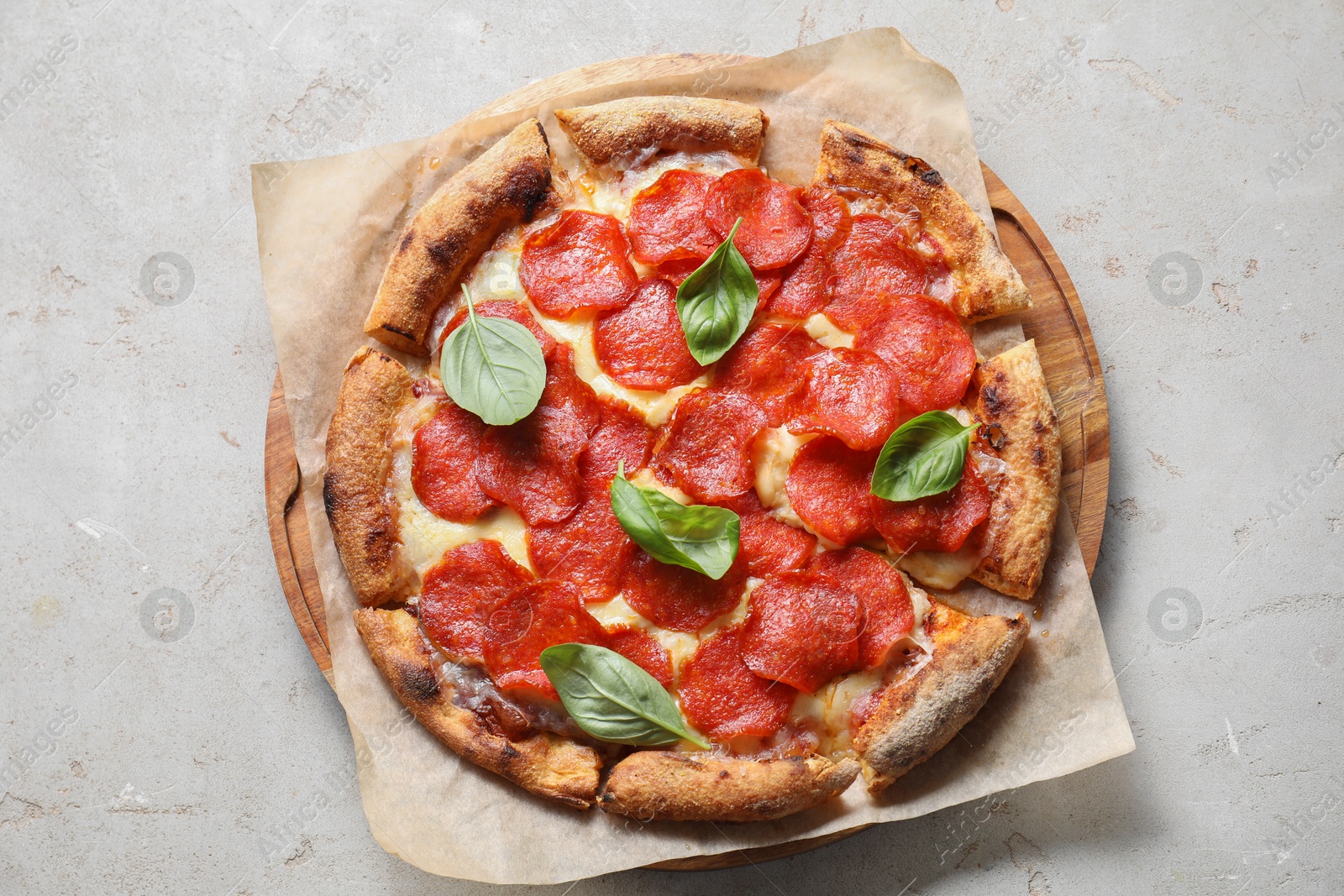 Photo of Tasty pepperoni pizza with basil on light grey table, top view