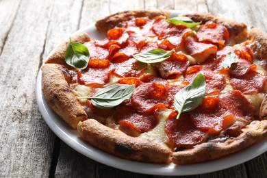 Tasty pepperoni pizza with basil on wooden table, closeup