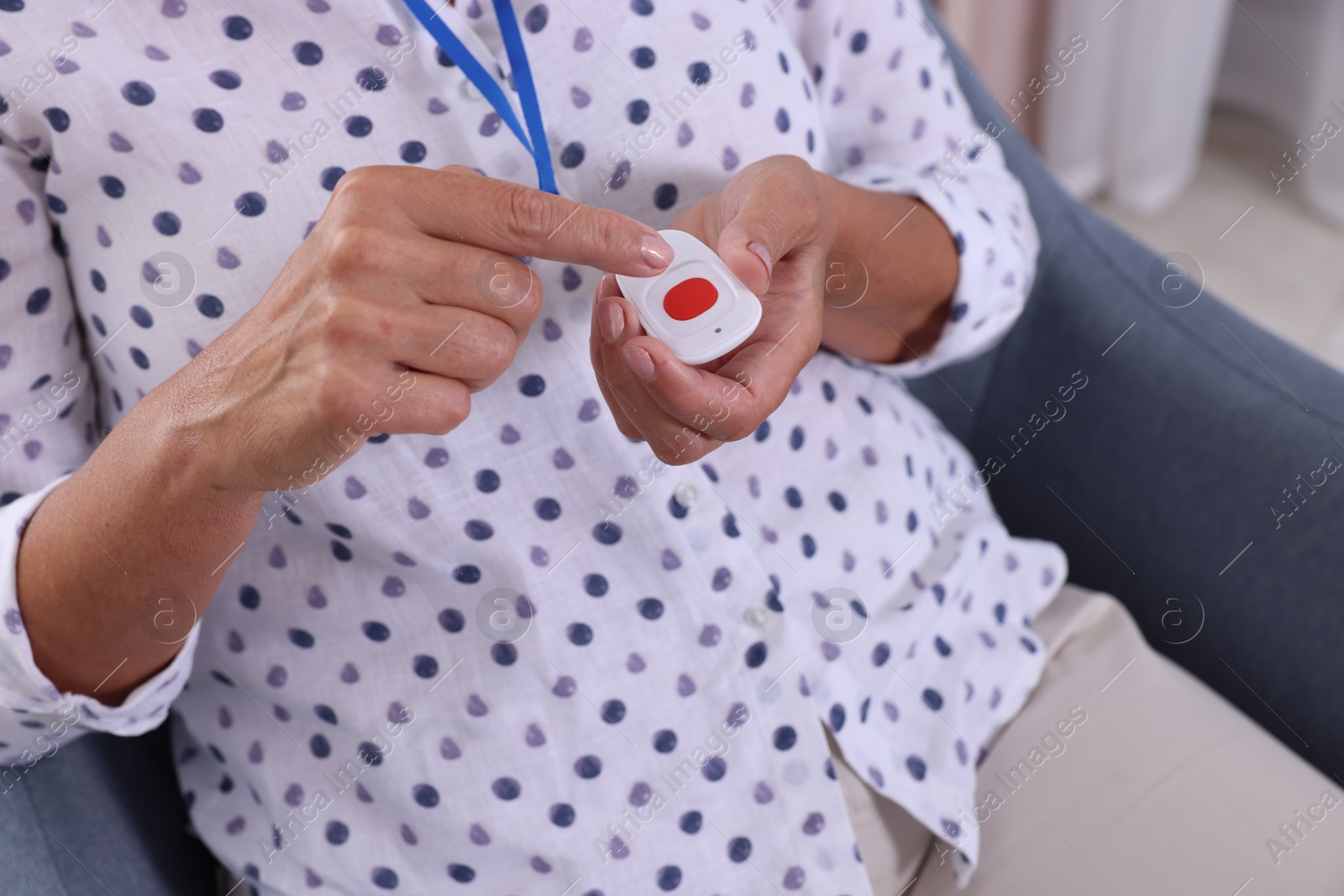 Photo of Senior woman pressing emergency call button at home, closeup