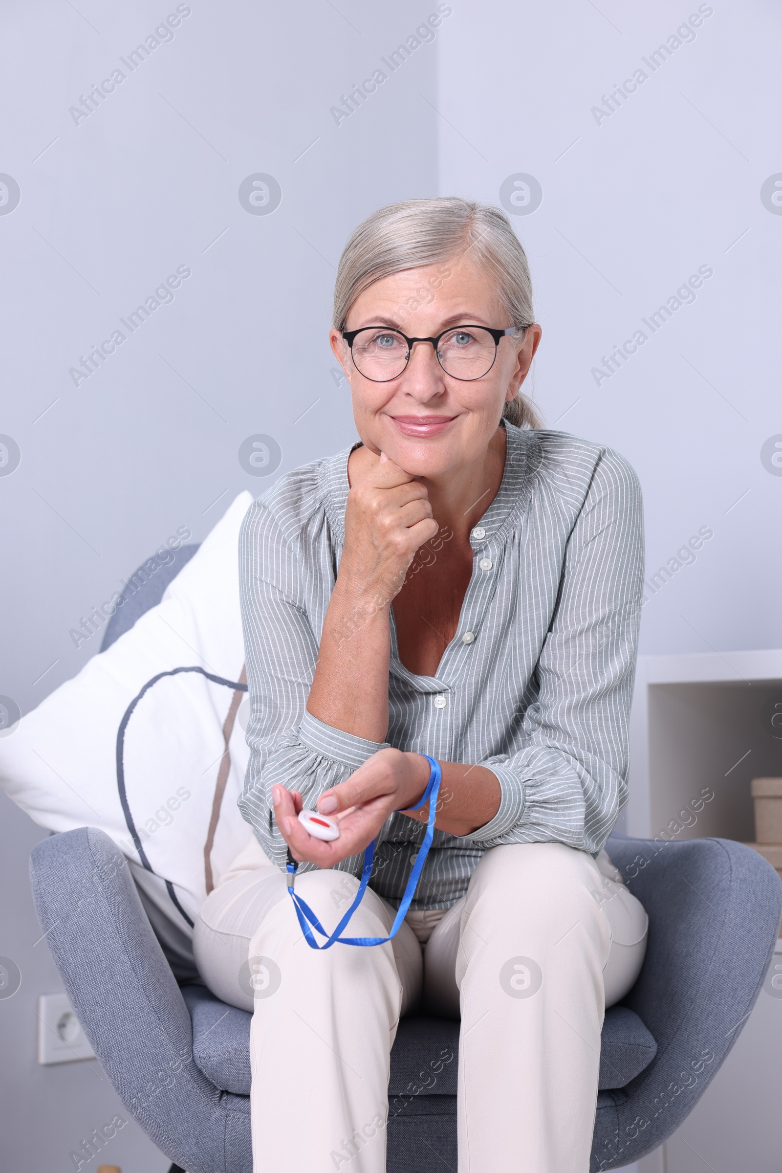 Photo of Senior woman with emergency call button at home