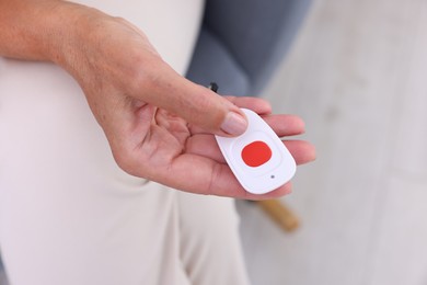 Photo of Senior woman with emergency call button at home, closeup