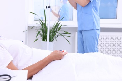 Photo of Senior woman with emergency call button and nurse setting IV drip in hospital, closeup