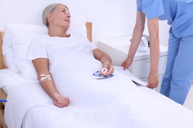 Senior woman with emergency call button and nurse in hospital