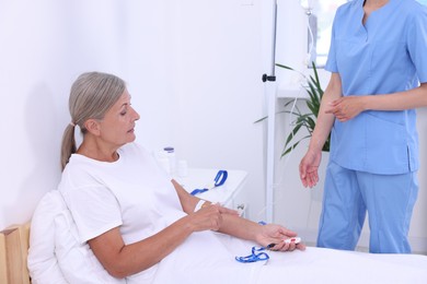 Nurse and senior woman talking about emergency call button in hospital, closeup