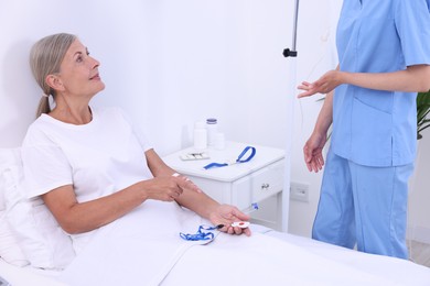 Photo of Nurse and senior woman talking about emergency call button in hospital, closeup