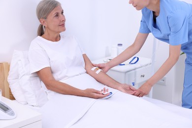 Senior woman with emergency call button and nurse in hospital