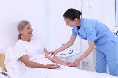 Senior woman with emergency call button and nurse in hospital