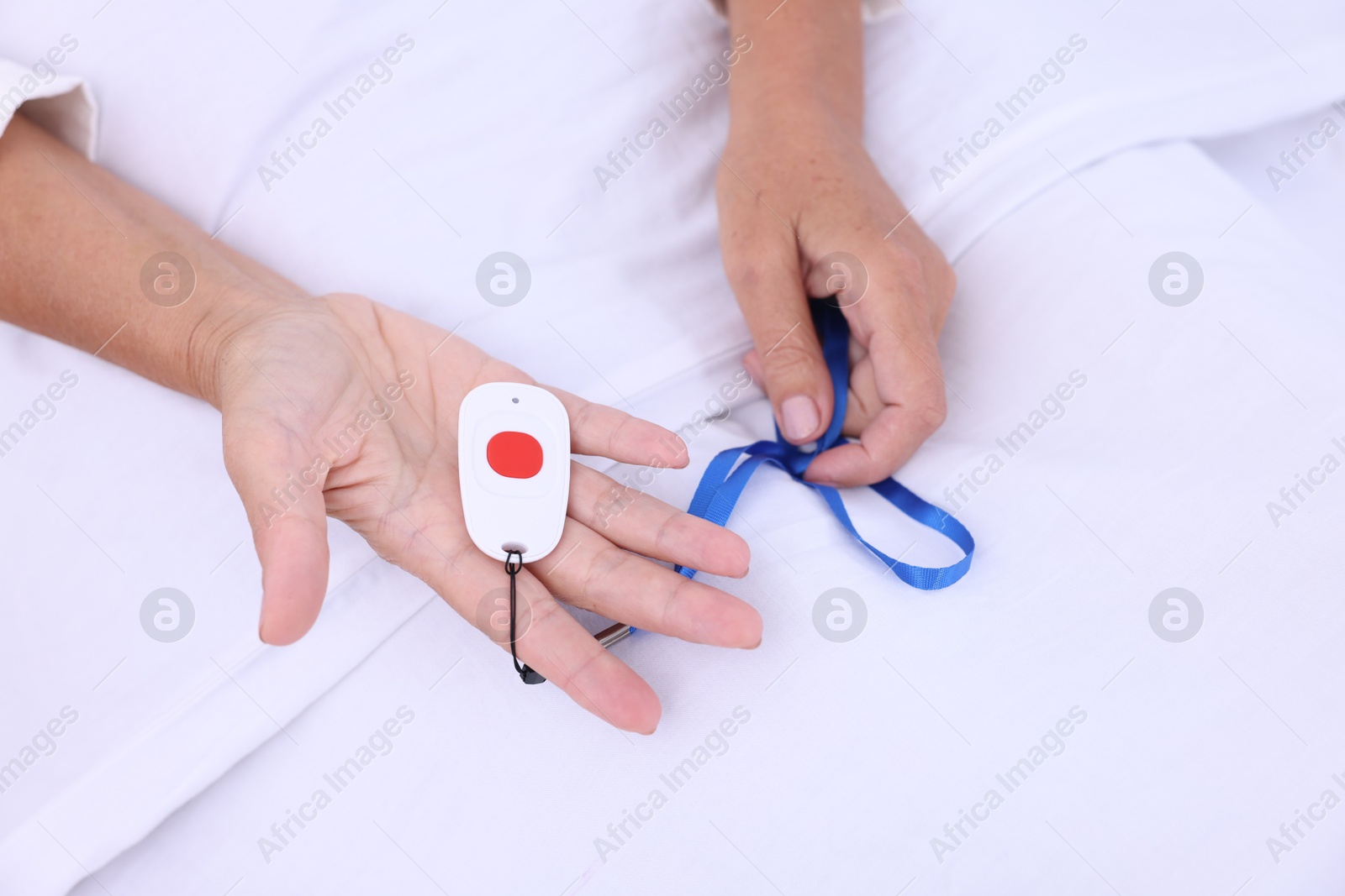 Photo of Senior woman with emergency call button on bed in hospital, top view