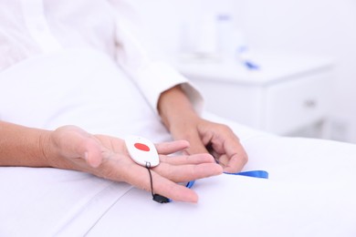 Photo of Senior woman with emergency call button on bed in hospital, closeup