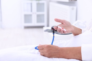 Photo of Senior woman with emergency call button on bed in hospital, closeup. Space for text