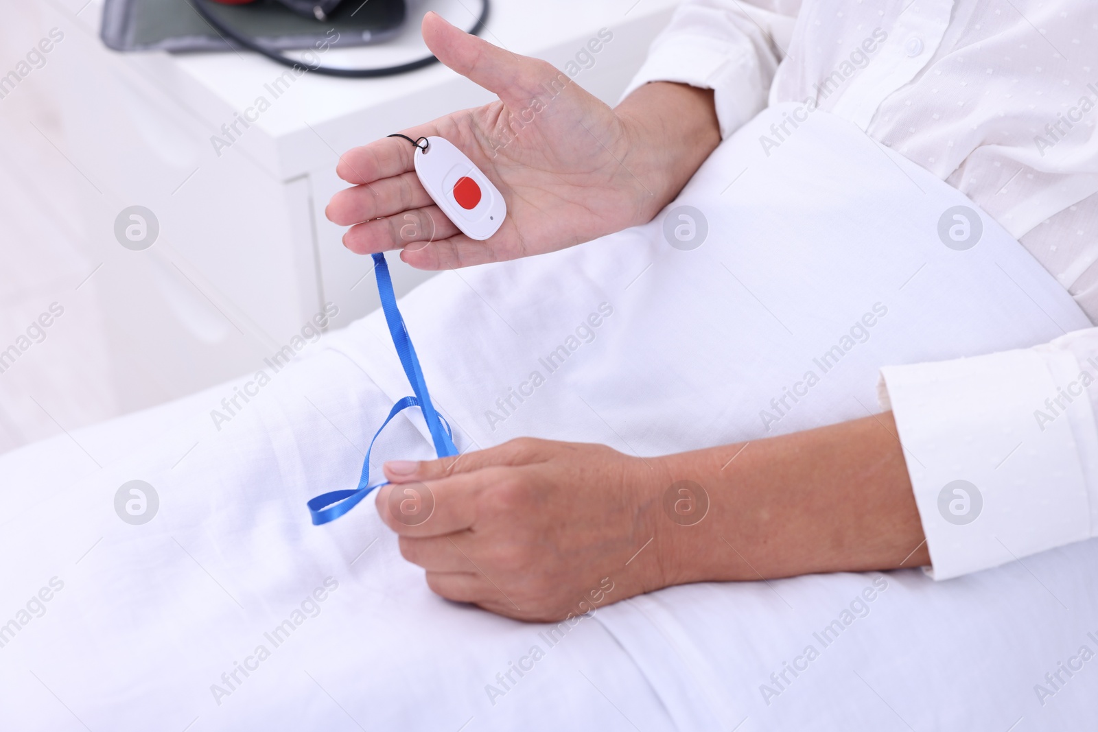 Photo of Senior woman with emergency call button on bed in hospital, closeup