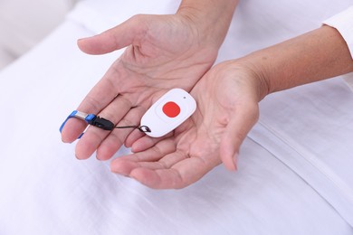 Photo of Senior woman with emergency call button on bed, closeup