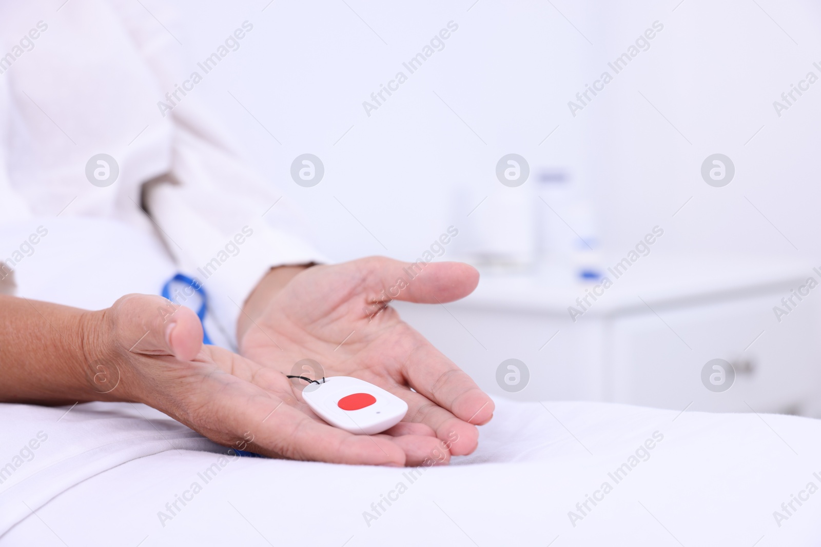 Photo of Senior woman with emergency call button on bed in hospital, closeup