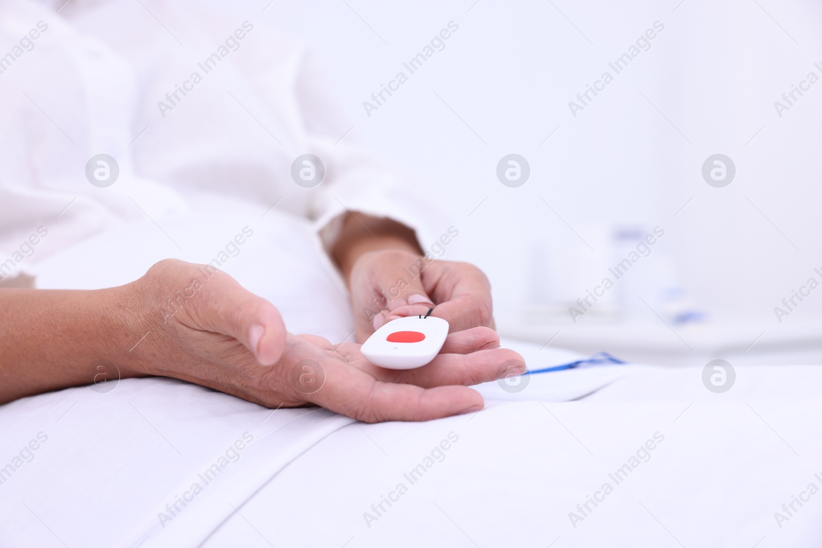 Photo of Senior woman with emergency call button on bed in hospital, closeup