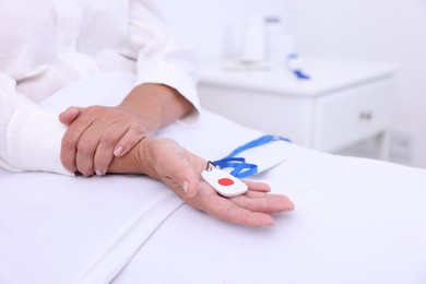 Photo of Senior woman with emergency call button on bed in hospital, closeup